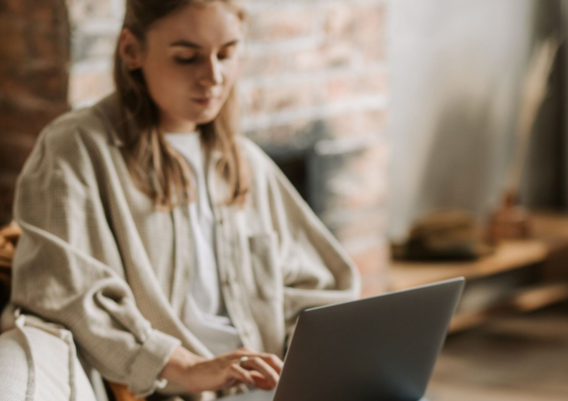 En ung kvinna jobbar via sin laptop i hemmamiljö.