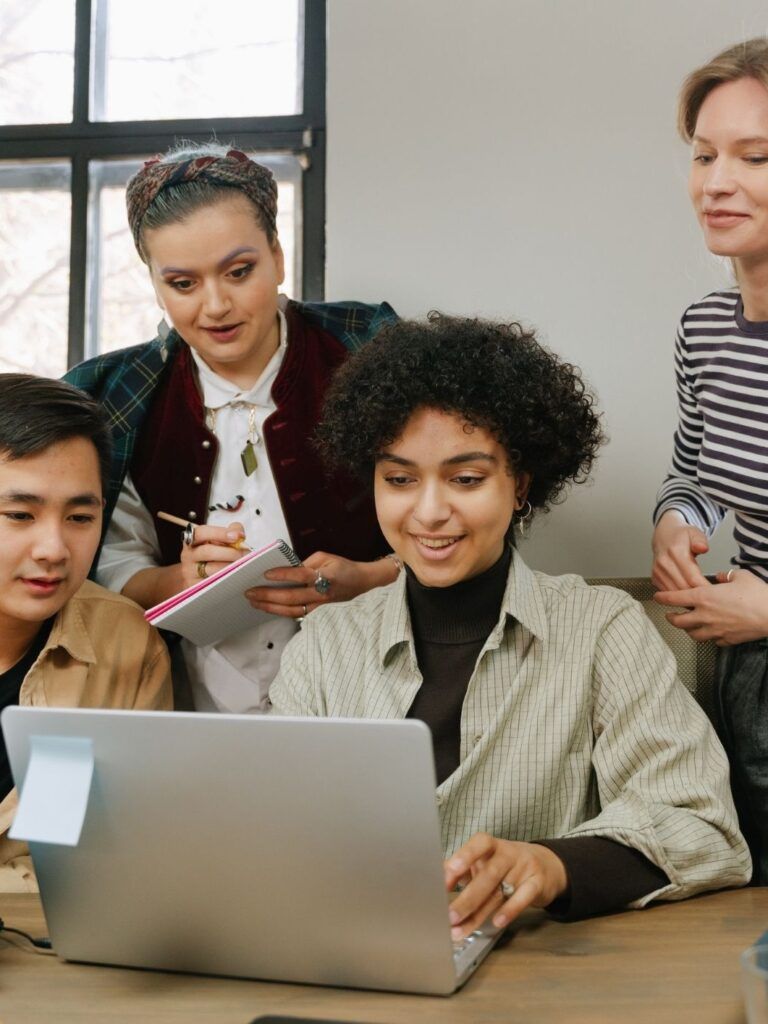 Fyra unga medarbetare samarbetar framför en datorskärm i en ljus och modern kontorsmiljö