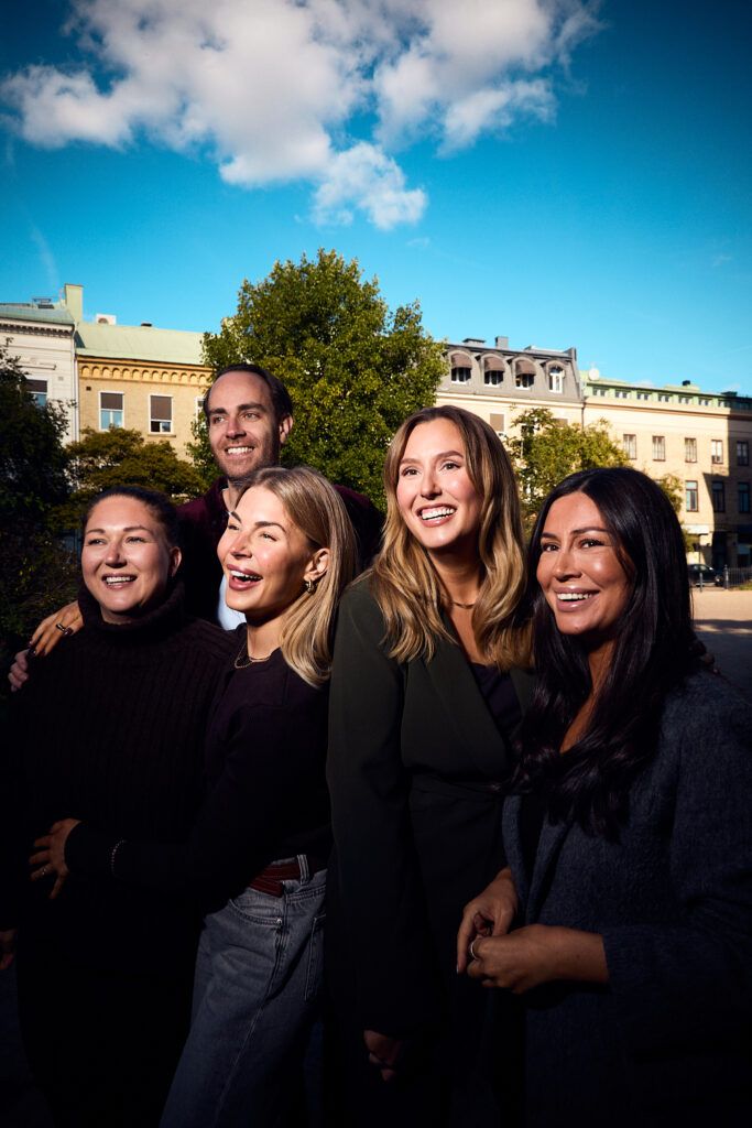 Fem glada medarbetare från Oddwork i solig utomhusmiljö.