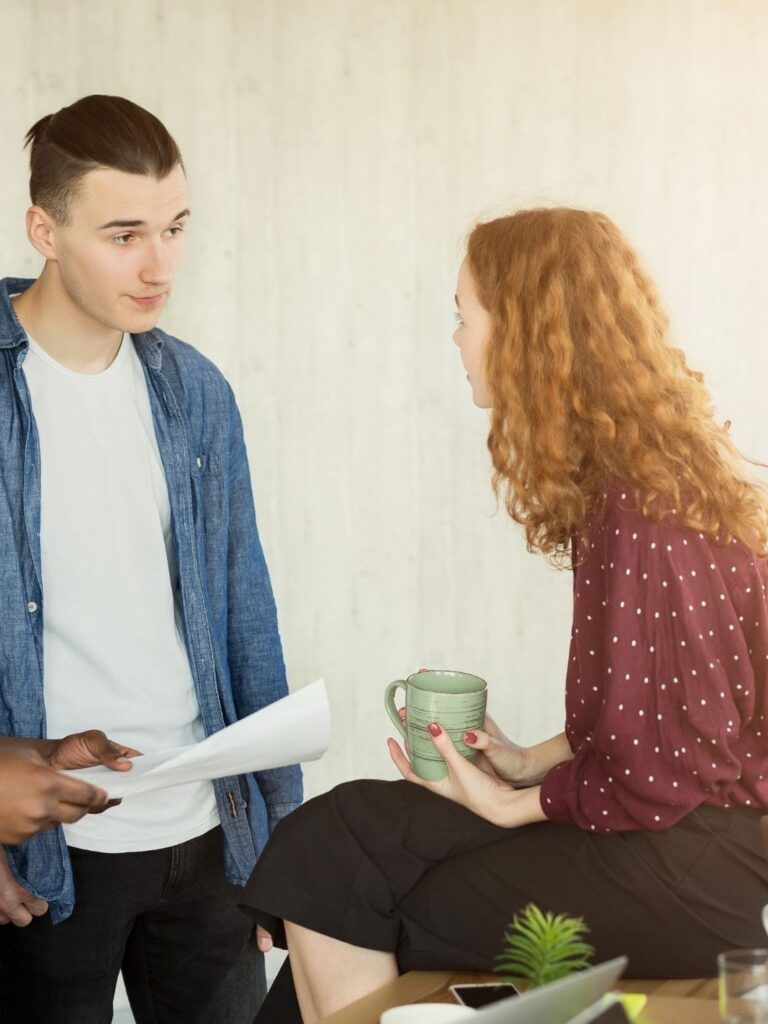 Tre unga medarbetare diskuterar och samarbetar.